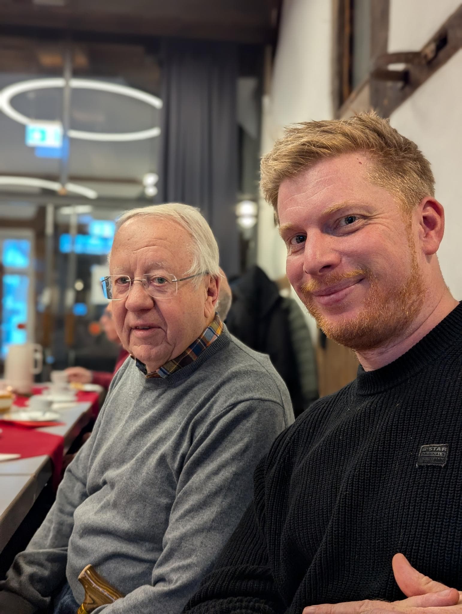 Zwei Gäste beim Adventskaffee, Kaffeetafel im Hintergrund